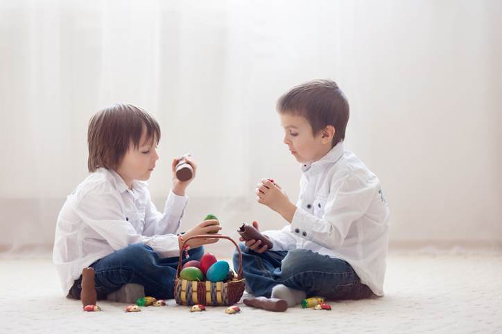 Two adorable little children, boy brothers, having fun eating chocolate bunnies