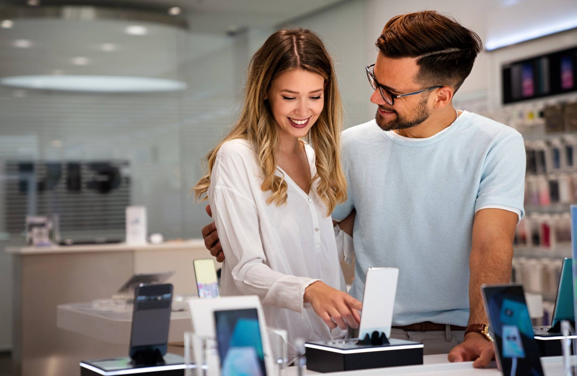 Tech shopping device gadget concept. Happy young people buying a new smartphone in mobile shop.