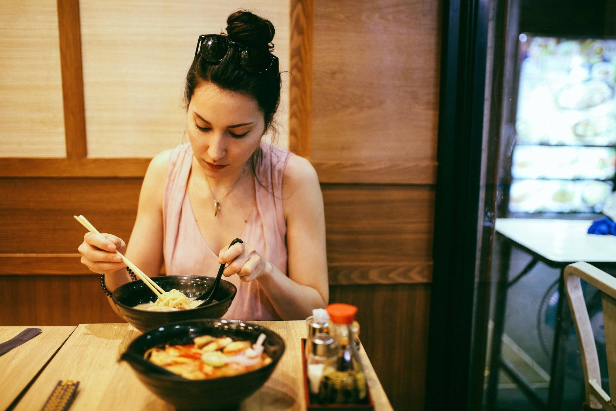 Young woman eating ramen noodles in a Japanese food place in Bangkok, Thailand
